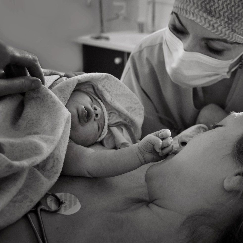 Jordemoder i selskab med nyfødt barn samt mor