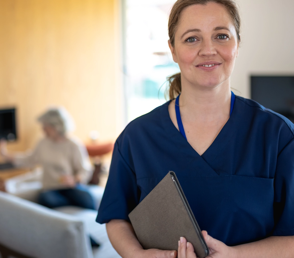 Smilende SOSU-assistent med tablet i hænderne