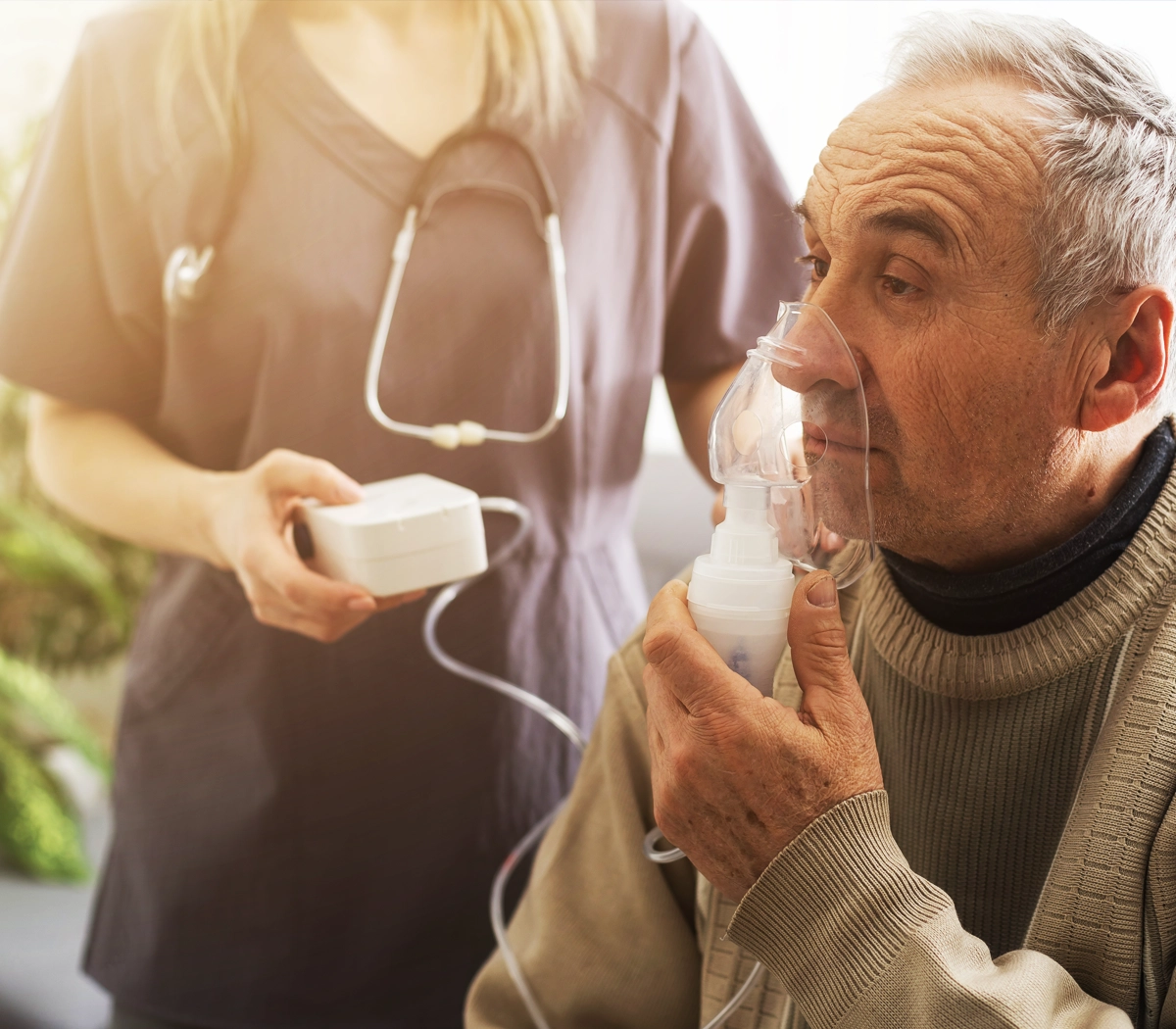 SOSU-assistent hjælper mand med inhalator